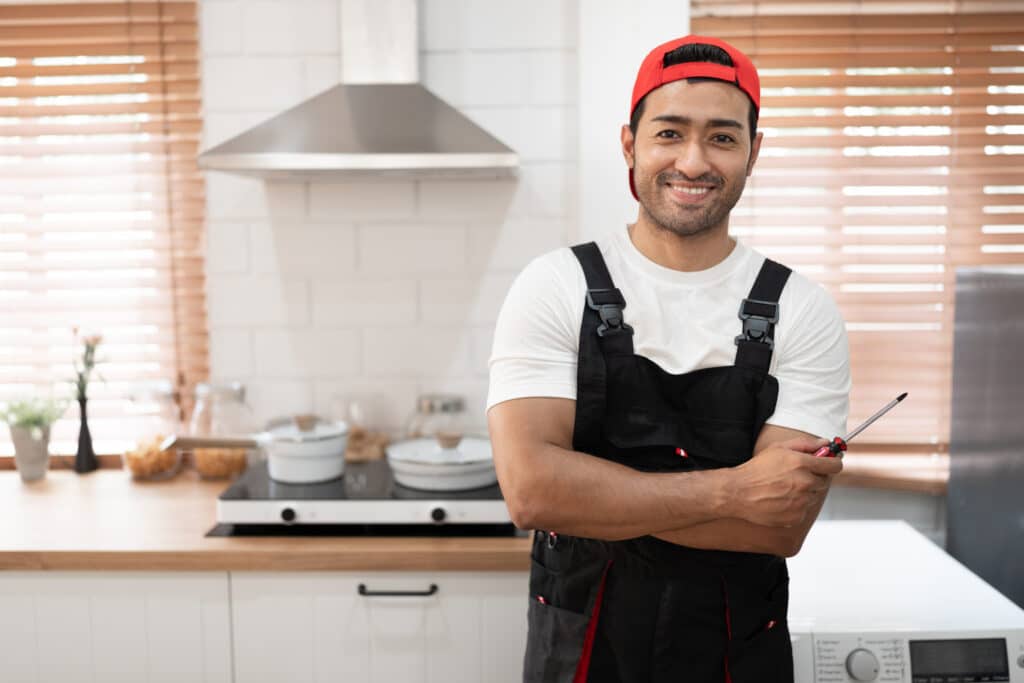 Friendly professional plumber standing in a kitchen after completing a residential service call for Burke Plumbing & Heating