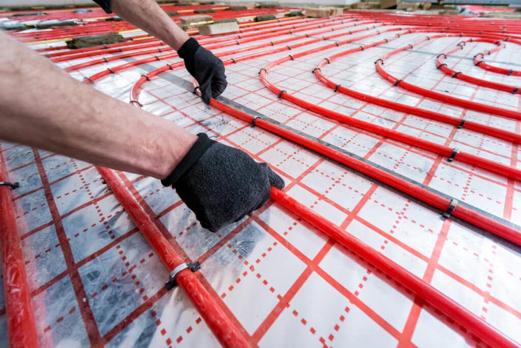 Technician installing radiant floor heating tubing during a residential heating system installation.